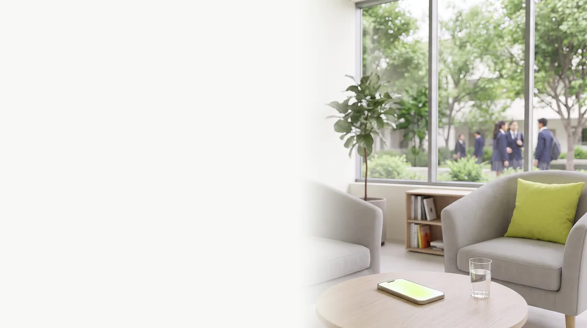 A quiet counsellor’s room at an international school: two armchairs, a lime cushion, a phone glowing on the table, students in the courtyard outside